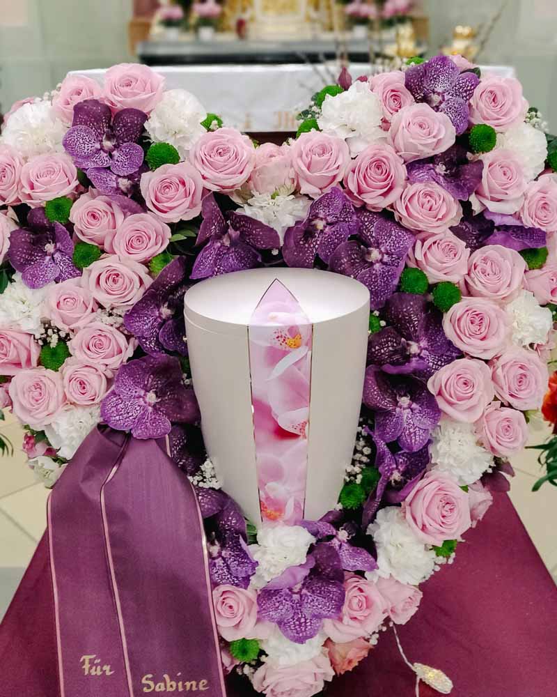 Urne in einem Herz aus Rosen.